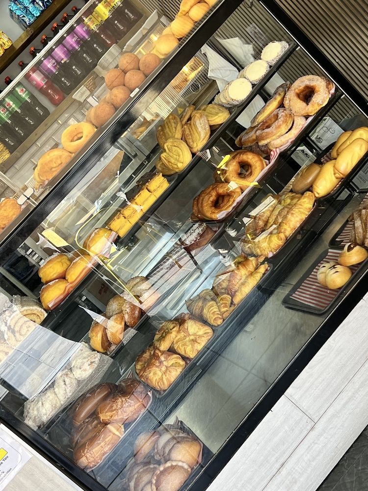 The glass cabinet along the counter, filled with doughnuts, rolls, croissants and Colombian pastries